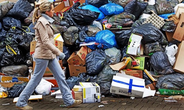 Пешеходка минава край огромна купчина боклуци в центъра на Амстердам. Служителите по чистотата в града обявиха едноседмична стачка с искания за по-високо заплащане и по-добри условия на труд. Снимка: БГНЕС