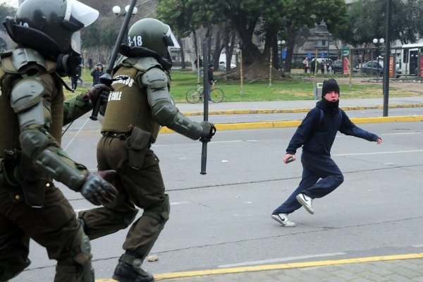 Полицаи гонят протестиращ студент в центъра на столицата на Чили – Сантяго. За пореден ден студенти протестираха срещу реформата в сектора на висшето образование. Снимка: БТА