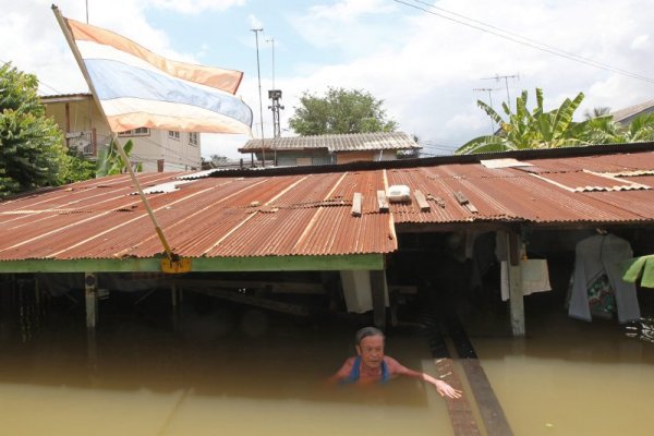 Тайландец плува около къщата си, която е залята от вода в провинция Аятая. Тежките наводнения в тази част от страната засегнаха хиляди хора. Снимка: БТА