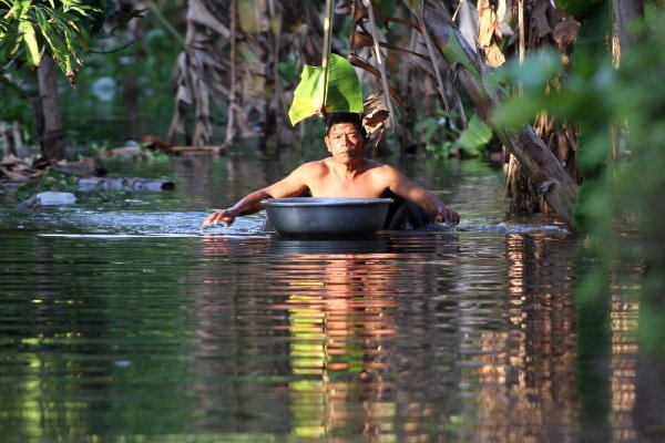 Мъж плува по улиците на село в Камбоджа, залети от прелялата река Меконг. Над милион и половина души пострадаха след природното бедствие. Снимка: БТА