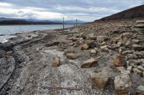 По бреговете са се показали огромни ивици земя, а от водата стърчат стълбове от някогашен далекопровод в село Живовци, останало на дъното при строежа на язовира преди 30 години.