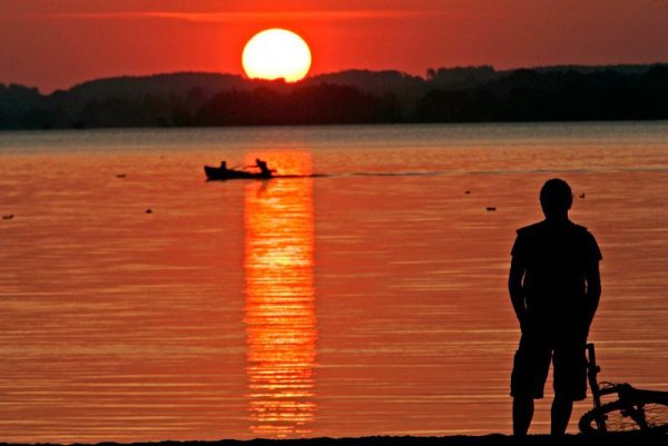 Велосипедист се наслаждава на залеза над езерото Кимзее в Германия. Снимка: БТА