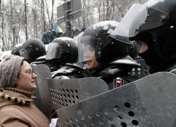 Жена разговаря с полицаи в центъра на Киев. Украинското вътрешно министерство съобщи, че при сблъсъците между протестиращите и милицията близо до стадион &quot;Динамо&quot; са пострадали 167 сътрудници на правоохранителните органи, като 84 от тях са настанени в болница с черепно-мозъчни травми. Снимка: БТА