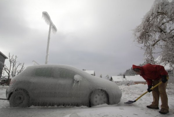 Мъж се опитва да изчисти заледената си кола в Постойна. Снимка: Reuters