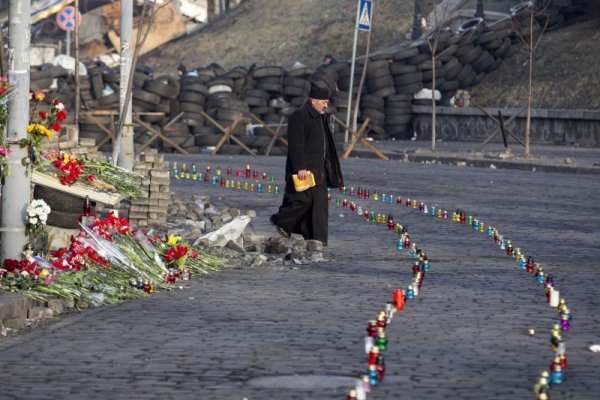 Свещеник минава по алея с цветя и свещи в памет на загиналите по време на протестите, изградена в близост до площад Независимост в Киев. Снимка: Reuters