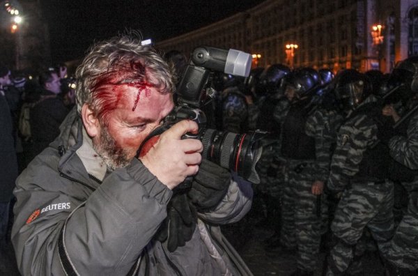 Раненият фотограф на Reuters Глеб Гаранич прави снимки, докато полицаи блокират протестиращите в Киев на 30 ноември 2013 година. Снимка: Reuters