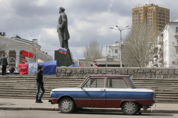 Мъж преминава покрай легендарната съветска кола &quot;Запорожец&quot;, боядисана в цветовете на руското знаме, в центъра на Донецк. Ситуацията в тази част от Украйна остава крайно нестабилна след сблъсъците в последните дни. Снимка: БТА