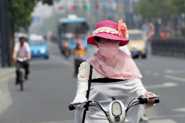 Китайка се пази от жежкото слънце, докато кара мотопед в провинция Джянсу. Снимка: БТА