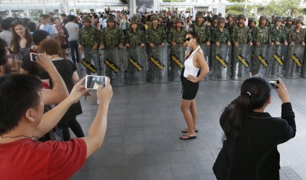 Тайландка позира на фона на войници в Банкок. Снимка: Reuters