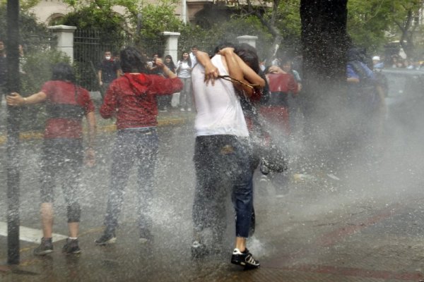 Ученици са залети с вода по време на митинг срещу затварянето на техните училища в Сантяго, Чили. Снимка: Reuters