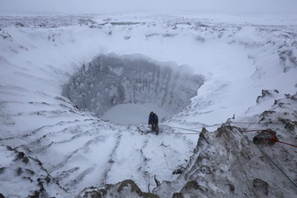 Член на изследователска експедиция стои на ръба на новообразуван кратер на полуостров Ямал, Северен Сибир. Геолози, историци и други учени все още не могат да стигнат до консенсус за произхода на кратера. Снимка: Reuters