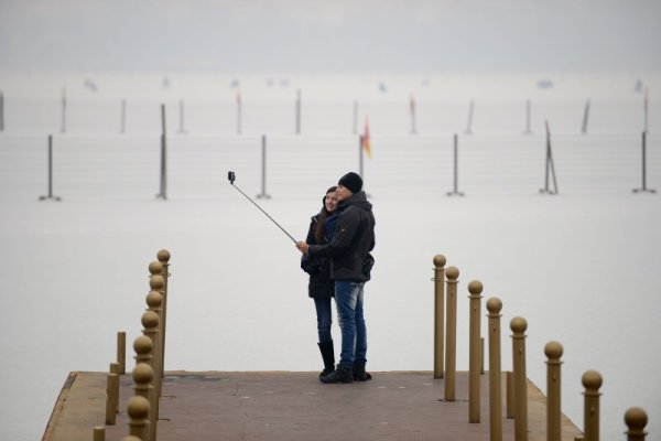 Туристи се снимат сами край замръзнало езеро в летния дворец в Пекин. Снимка: БТА