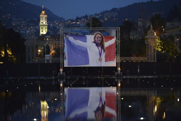 Огромна снимка на френската състезателка по плуване Камий Муфа бе поставена в нейния роден град Ница. 25-годишната звезда на френското плуване, която е олимпийската шампионка от Лондон 2012 в дисциплината 400 метра свободен стил, загина в авиокатастрофа по време на снимки за реалити шоу в Аржентина. Снимка: Reuters