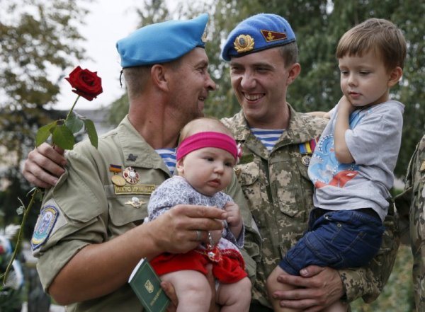 Украински войници са прегърнали децата си, след като са се завърнали от фронтовата линия в източната част на страната. Снимка: Reuters