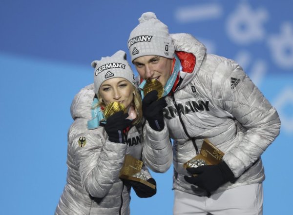 Златните медалисти при спортните двойки във фигурното пързаляне Альона Савченко и Брюно Масо целуват своите отличия по време на церемония по награждаването в Пьонгчанг. Снимка: БТА