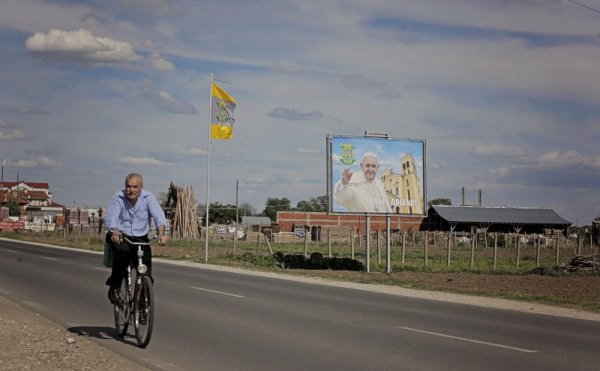 Мъж кара колело на входа на град Раковски на фона на билборд с надпис &quot;Добре дошъл&quot; и лика на папа Франциск. Градът ще посрещне главата на Римокатолическата църква на 6 май. Снимка: БТА