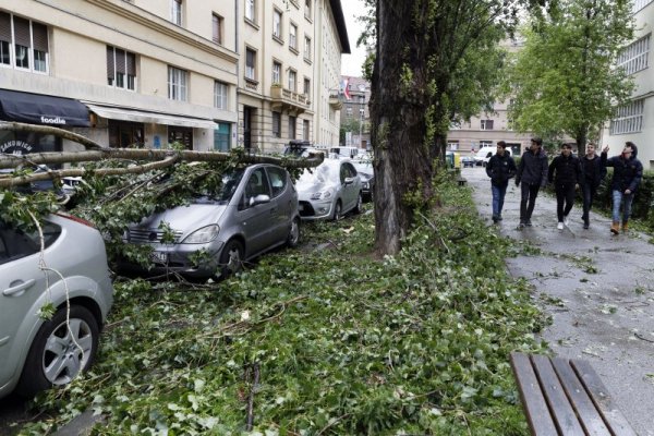 Ученици преминават покрай част от дърво, паднало върху кола, в столицата на Хърватия Загреб. По улиците във всички части на града тази сутрин има много изкоренени дървета и изпочупени клони, разхвърляни кофи за боклук и дървени щандове. Снимка: БТА