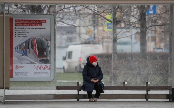 Възрастна жена с маска стои сама на пейка на спирка на градския транспорт. Снимка: БГНЕС