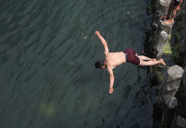 Млад мъж се разхлажда, като скача във водите на езеро край индийския град Шринагар. Снимка: БГНЕС