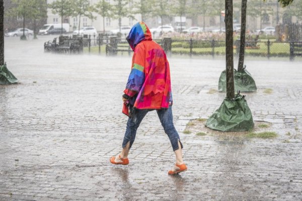 Млада жена върви смело сред поройния дъжд, който вали в датската столица Копенхаген. Снимка: БГНЕС