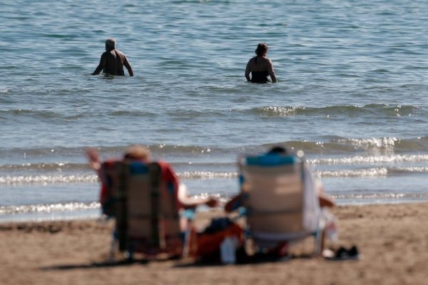 Възрастна двойка влиза да се изкъпе в морската вода на плаж във Валенсия. Топлото време и слънцето изкараха най-големите мераклии на слънце и разходка край морето. Снимка: БГНЕС