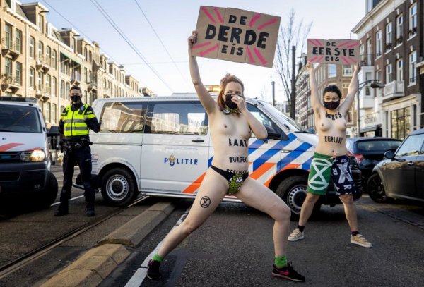 Голи демонстрантки от екологичното движение &quot;Extinction Rebellion&quot; протестират в Амстердам пред погледа на органите на реда, които малко по-късно се опитаха да премахнат протестиращите. Снимка: БГНЕС