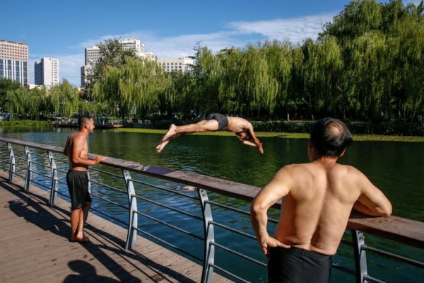 Мъж скача от мост в река в Пекин. Температурите на много места в Китай в последните дни скочиха над 40 градуса. Снимка: БГНЕС